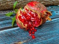 Opened pomegranate with scattered seeds on a blue hue wooden table. Royalty Free Stock Photo